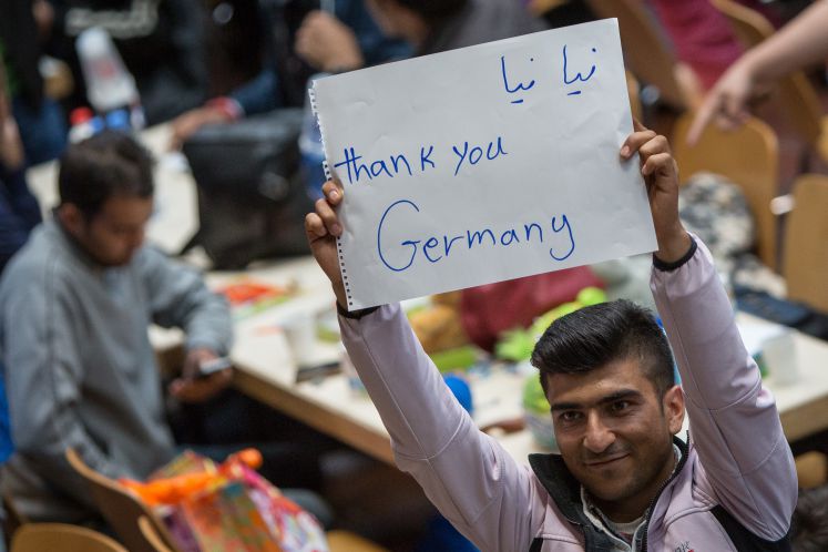 A refugge holds up a sign on which he wrote "Thank you Germany"