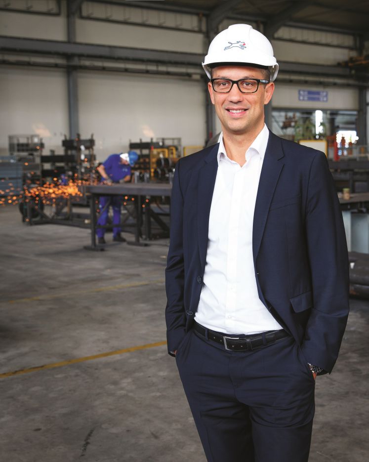 Christian Pokropp in seiner Fabrik mit Anzug und Schutzhelm