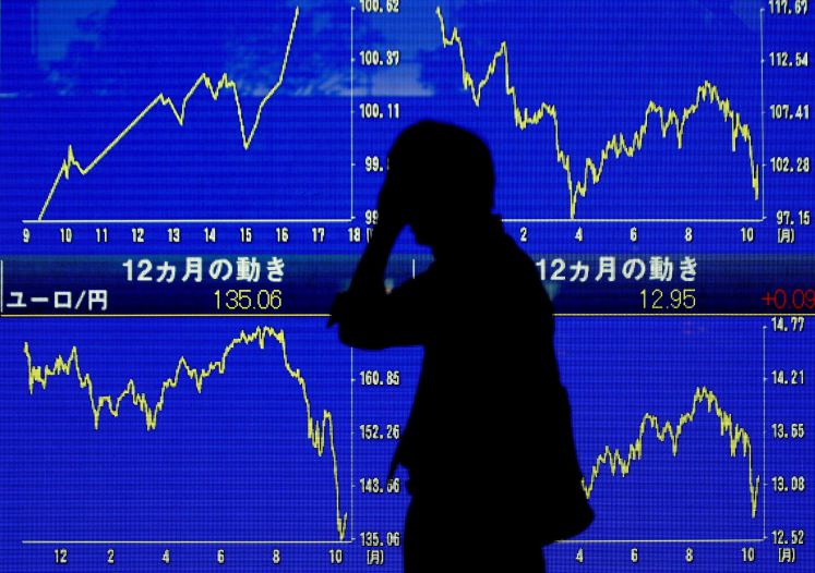 Ein Geschäftsmann geht vorbei am Nikkei-Index, der drastische Kurseinbrüche verzeichnet