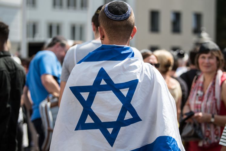  In eine israelische Fahne eingewickelt demonstriert ein Mann auf dem Marktplatz gegen Antisemitismus.