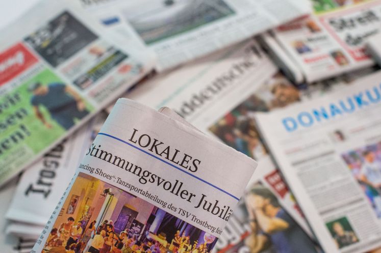  Eine Lokalzeitung wird über andere Zeitungen gehalten.
