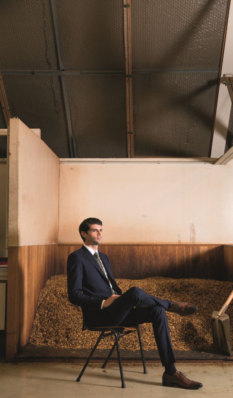 Nils Obermann sitzt in einem Anzug vor einer Ladung Tabak