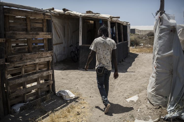 21.07.2018, Spanien, Almería, Nijar: Ein Migrant geht durch ein Flüchtlingscamp. Mehr als 50 afrikanische Migranten leben unter schlechten Bedingungen in einem Camp, einer Dauersiedlung, nahe der spanischen Stadt Nijar'und hoffen, auf den nahegelegenden Plantagen, Arbeit zu finden.