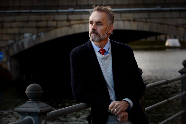 Jordan Peterson in Helsinki, Finnland, an ein Geländer vor einem Fluss gelehnt