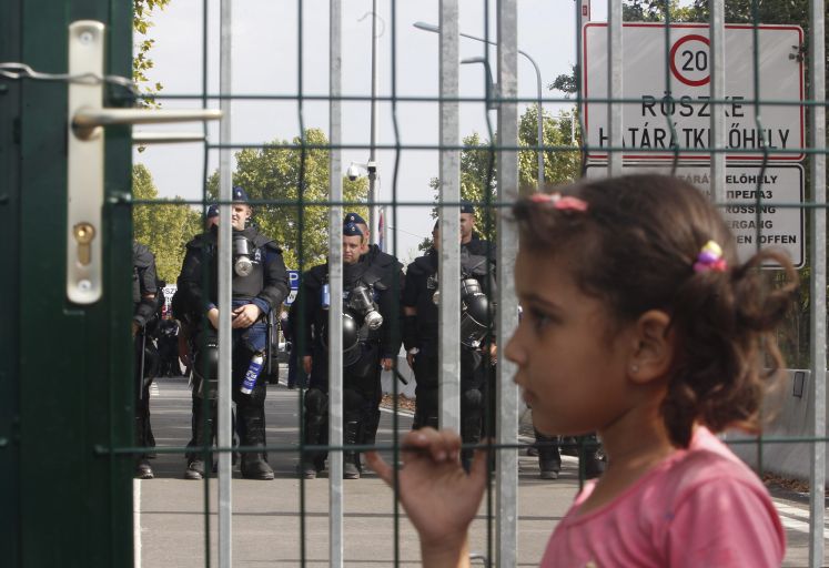 Ein kleines Mädchen steht am Grenzzaun der ungarischen Grenze zu Serbien