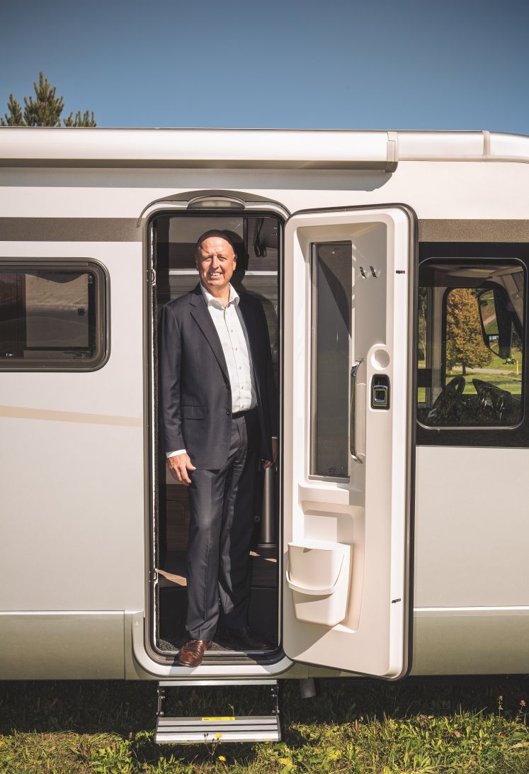 Martin Brandt steht in der Tür eines Wohnwagens und lächelt in die Kamera