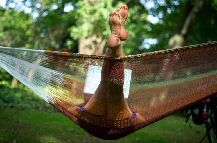 Eine Frau liegt am 20.06.2017 in einem Park in Berlin beim sommerlichen Wetter in ihrer Hängematte und arbeitet auf ihrem Laptop