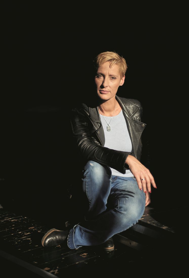 Dorotty Szalma sitzt vor schwarzem Hintergrund auf einer Treppe