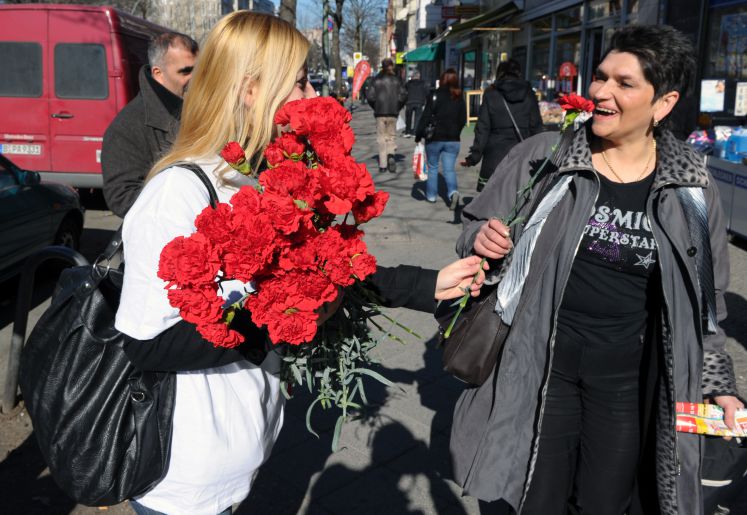 Eine Mitarbeiterin des Türkischen Bundes Berlin-Brandenburg, Meltem Köyeasi (l), überreicht am Dienstag (08.03.2011) auf dem Kottbusser Damm in Berlin rote Nelken an eine Frau. Insgesamt verteilte der Bund 1.000 Nelken auf der Einkaufsstraße im Stadtteil Kreuzberg. Der 8. März ist der Internationale Frauentag