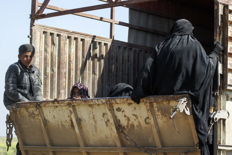 20.02.2019, Syrien, Baghus: Frauen und Kinder fahren auf einem Lastwagen eines Konvois, welcher Zivilisten und Familienangehörige von IS-Kämpfern aus der letzten Bastion der IS in ein Zwischenlager evakuiert. Etwa 30 Lastwagen der kurdisch geführten Syrischen Demokratischen Kräfte (SDF) verließen den umzingelten Ortsteil von Baghus im Osten Syriens.