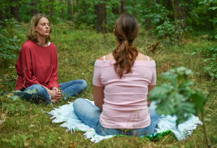 15.08.2018, Brandenburg, Basdorf: Pia Hötzl (l), Glückslehrerin, Coach und Heilpraktikerin der Psychotherapie, sitzt beim sogenannten «Waldbaden» mit einer Klientin mitten in einem Wald. 