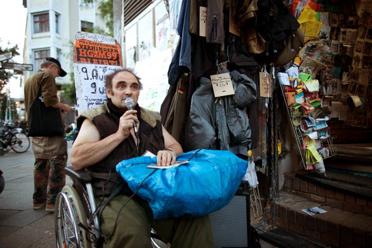 Besitzer Hans-Georg Lindenau spricht bei einer Kundgebung für den Erhalt seines Ladengeschäfts «M99 Gemischtwaren mit Revolutionsbedarf» am 28.07.2016 in Berlin. Dem Laden droht am 09.08.2016 die Zwangsräumung. Damit würde der auf einen Rollstuhl angewiesene Lindenau nicht nur seine Arbeitsmöglichkeit, sondern auch die auf seine Bedürfnisse zugeschnittene Wohnung verlieren.