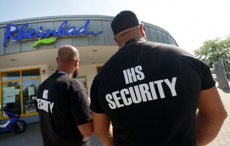 29.07.2019, Nordrhein-Westfalen, Düsseldorf: Zwei Männer des Sicherheitsdienstes IHS Security stehen vor dem Eingang des Rheinbades. Nach wiederholten Tumulten im Düsseldorfer Rheinbad greift die Stadt durch: Es wird neben einer Ausweispflicht auch Videoüberwachung und Unterstützung durch das Ordnungsamt geben 