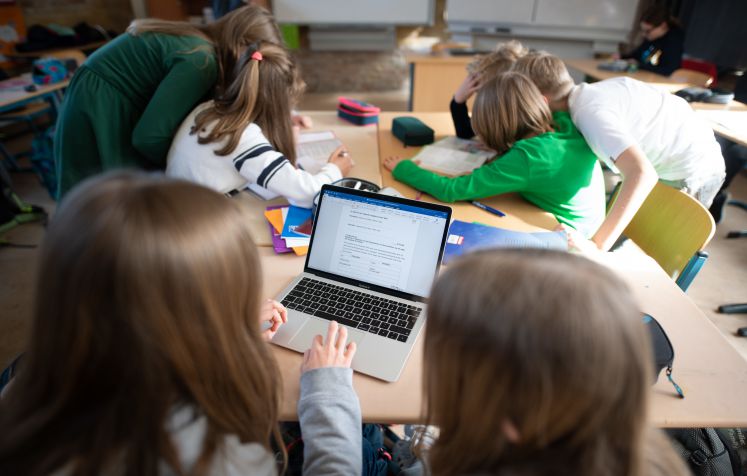  Schüler einer fünften Klasse eines Gymnasiums benutzen im Unterricht einen Laptop.