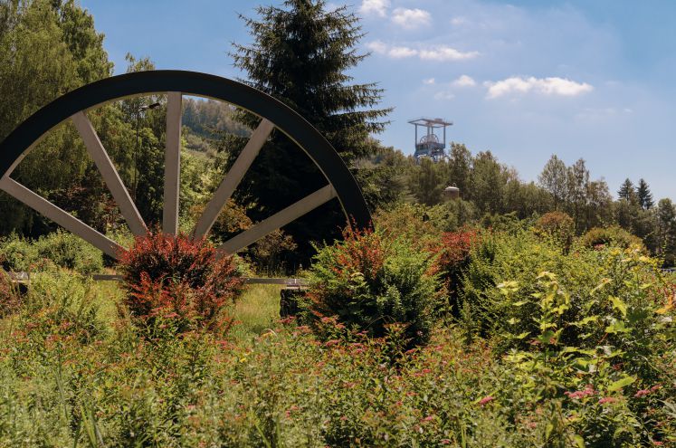 Förderturm und großes Rad in grüner Landschaft