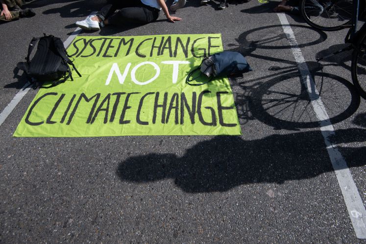 20.09.2019, Baden-Württemberg, Stuttgart: Ein Transparent mit der Aufschrift "System Change not Climate Change" liegt während einer Blockade auf einer Straße. Die Demonstranten folgen dem Aufruf der Bewegung Fridays for Future und wollen für mehr Klimaschutz kämpfen. Sie wollen damit die Streik- und Protestaufrufe in der ganzen Welt unterstützen.