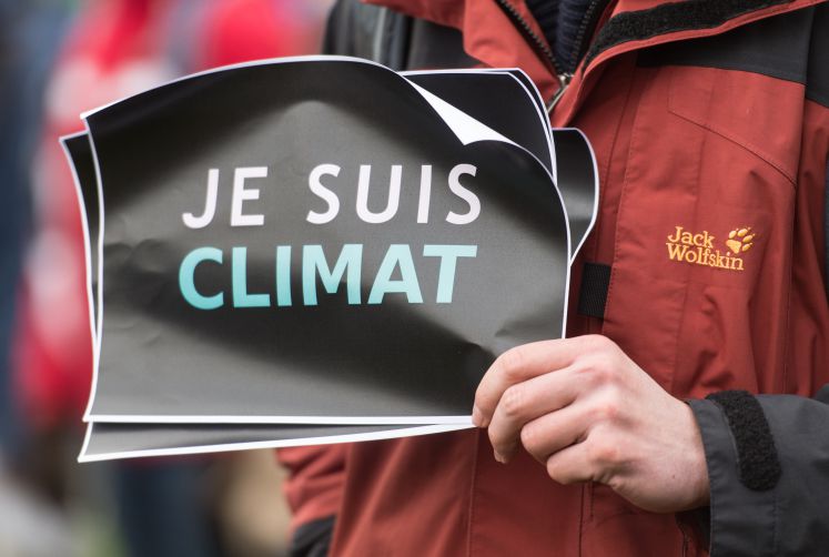 Ein Demonstrant hält ein Schild mit der Aufschrift "Je suis Climat".