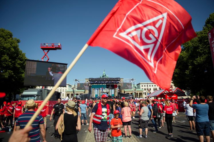 Teilnehmer stehen während einer Großkundgebung der Gewerkschaft IG Metall für einen sozialverträglichen Umbau der Industrie und die arbeitsplatzsichernde Energie- und Verkehrswende vor dem Brandenburger Tor auf der Straße des 17. Juni.