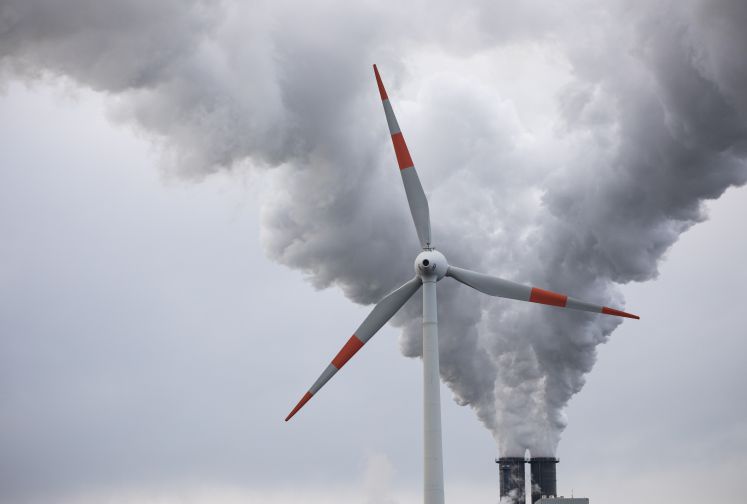 04.11.2019, Hamburg: Abluft steigt aus den Schornsteinen des Kohlekraftwerks Moorburg hinter einem Windrad in den Himmel. Der Energiekonzern Vattenfall betreibt in Hamburg-Moorburg eines der größten und modernsten Kohlekraftwerke Europas. 