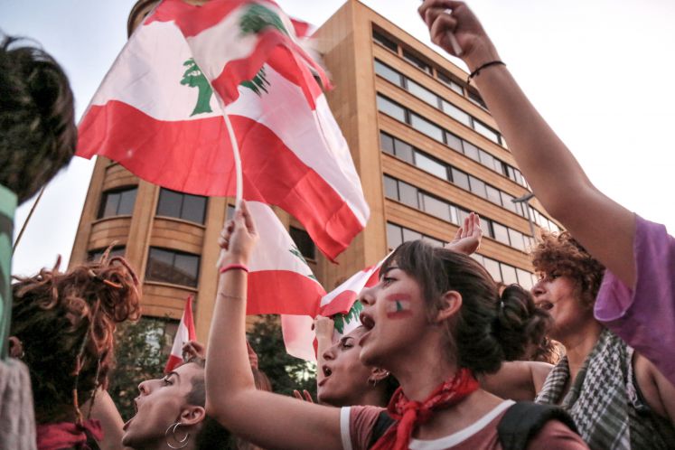 19.10.2019, Libanon, Beirut: Frauen rufen Slogans und schwenken die libanesische Fahnen bei einer Demonstration in der Innenstadt.