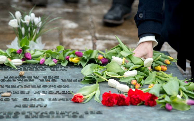 04.03.2018, Niedersachsen, Lohheide: Angehörige und Besucher legen Blumen an einer Tafel in der Gedenkstätte Bergen-Belsen ab. Mit einer Gedenkveranstaltung wurde hier an den Völkermord an den Sinti und Roma während des Nationalsozialismus erinnert. (zu dpa "Gedenkveranstaltung erinnert an Völkermord an Sinti und Roma" vom 04.03.2018