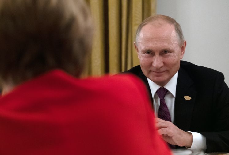 Grinsender Wladimir Putin gegenüber von Angela Merkel