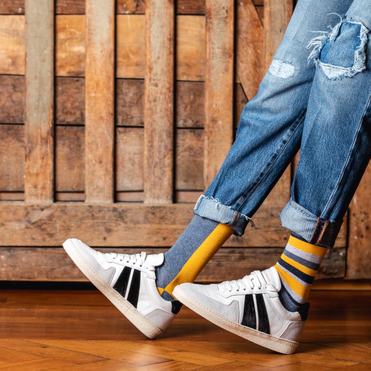 Füße mit bunten Socken und weißen Turnschuhen