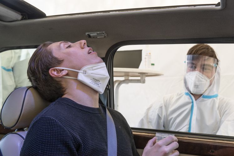 Zu Demonstrationszwecken zeigt ein Freiwilliger die Funktionsweise eines PCR-Tests mit Gurgeln. Dabei können Autofahrer im "Drive-In"-Verfahren in ihren Autos sitzen bleiben und müssen etwa 20 Sekunden lang mit einer Salzlösung gurgeln, die dann im Labor ausgewertet wird.