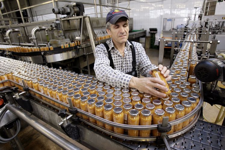 Mann am Fließband in einer Abfüllanlage für Smoothies