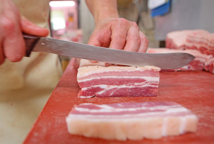 Metzger schneidet Schweinebauch