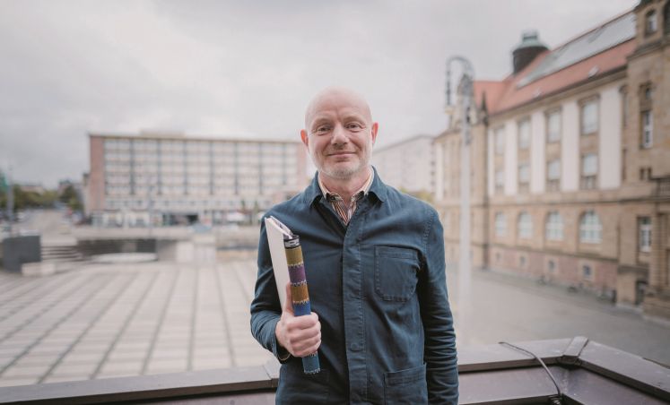 Stefan Schmidtke auf dem Theaterplatz mit Buch in der Hand