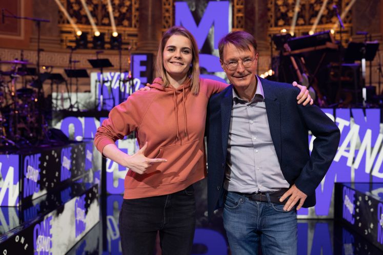 Karl Lauterbach (SPD), Gesundheitsminister, und schweizerisch-deutsche Stand-up-Comedian, stehen in der Kulisse von «One Mic Stand»