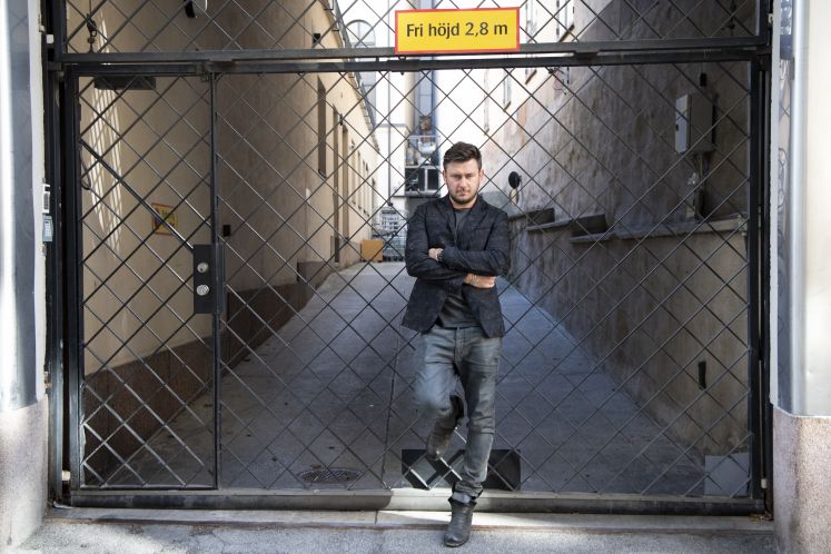 Schriftsteller Dmitry Glukhovsky steht mit verschränkten Armen an ein Gittertor gelehnt