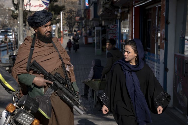 Ein bewaffneter Taliban läuft in Kabul mit einer Frau durch die Stadt