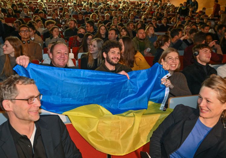 Studierende und Mitarbeiter der Europa-Universität Viadrina Frankfurt (Oder) warten mit der ukrainischen Nationalflagge in einem Hörsaal auf den Beginn einer Videoverbindung mit Wolodymyr Selenskyj