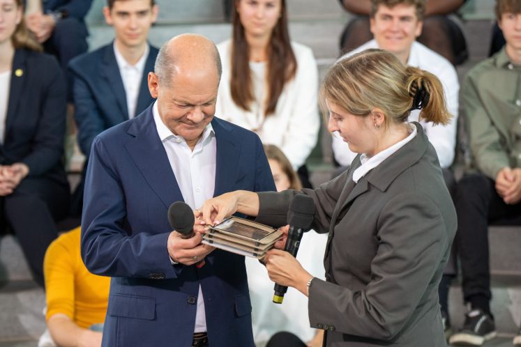 Bundeskanzler Olaf Scholz (SPD), lässt sich von Schülerin Charlotte Klar (r) ihr Experiment beim Empfang für die Teilnehmer am Schülerwettbewerb "Jugend forscht 2023" im Bundeskanzleramt erklären.