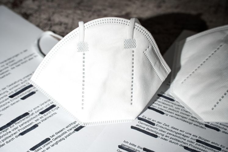 RKI-Protokolle zu Covid-19. Geschwärzte Dokumente mit FFP2-Maske