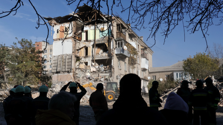 Rettungskräfte und Anwohner stehen vor einem Wohnhaus in Saporischschja, das durch einen russischen Luftangriff schwer beschädigt wurde.