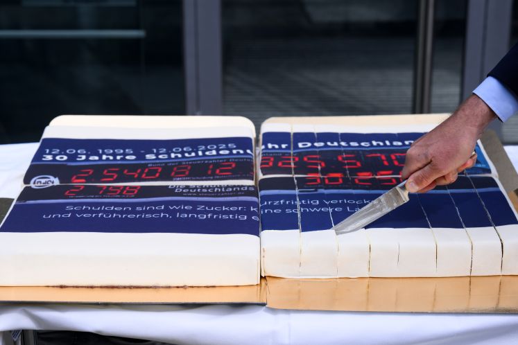 Mann schneidet einen Kuchen mit einer Schuldenuhr-Glasur an