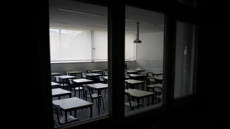 Leeres Klassenzimmer mit Tischen und Stühlen, Blick durch Fenster, Foto.