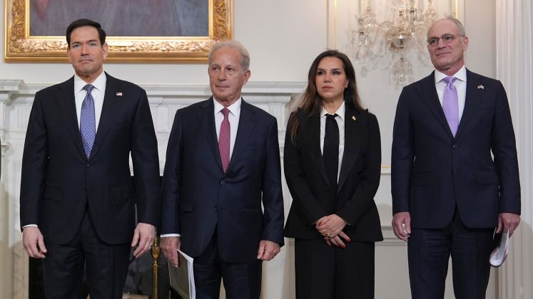 Vier Personen in Anzug und Kostüm stehen nebeneinander in elegantem Raum, Gruppenfoto, Foto.