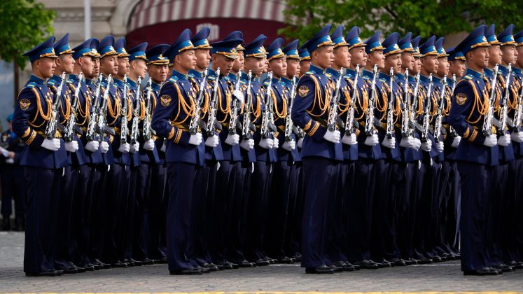 Mehrere uniformierte Soldaten marschieren in perfekter Formation auf einer Straße. Foto.