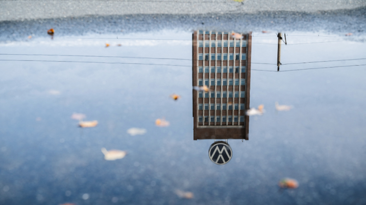 Das Markenhochhaus am VW-Stammwerk spiegelt sich in einer Pfütze