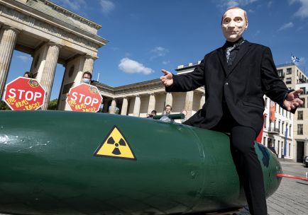Ein als russischer Präsident Putin verkleideter Aktivist fährt vor dem Brandenburger Tor während einer Demo für eine Welt ohne Atomwaffen auf einer fahrbaren Atombombe. 