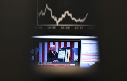 US-Präsident Trump ist auf einem Bildschirm auf dem Parkett der Frankfurter Wertpapierbörse vor der Anzeigetafel mit der Dax-Kurve zu sehen. 