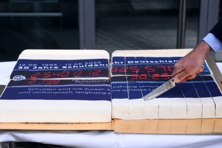 Mann schneidet einen Kuchen mit einer Schuldenuhr-Glasur an