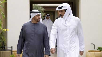 Zwei Männer in traditioneller arabischer Kleidung gehen nebeneinander, draußen, ernstes Gespräch. Foto.