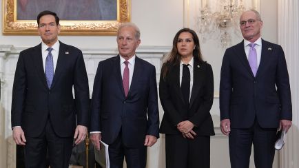Vier Personen in Anzug und Kostüm stehen nebeneinander in elegantem Raum, Gruppenfoto, Foto.