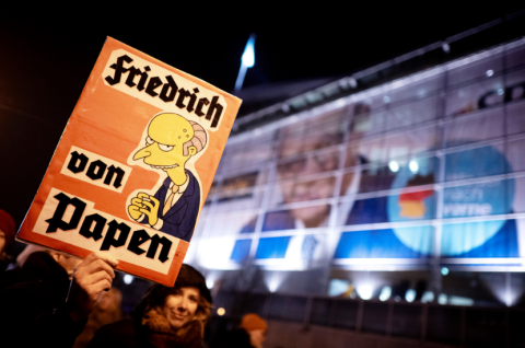 Auf einem Schild der Demonstranten wird Friedrich Merz in Anlehnung an Franz von Papen karikiert, den Reichskanzler, der Hitlers Machtübernahme begünstigte