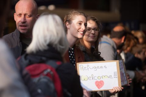 Mehrere Menschen stehen zusammen, eine Frau hält ein Schild, freundliche Atmosphäre, Foto.
